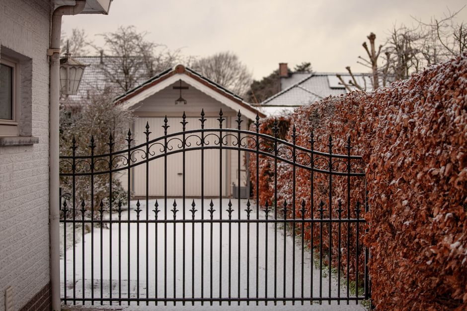A decorative iron gate in a courtyard with hedges.