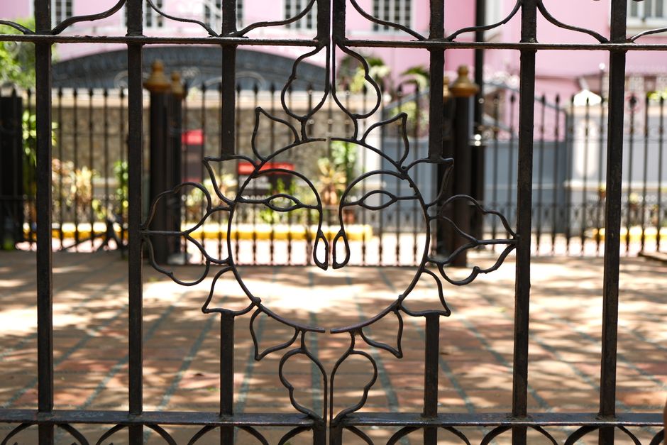 An iron gate featuring a sun design, in a courtyard.