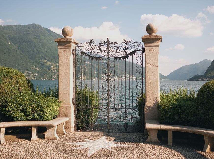 An ornate iron gate set in a garden.